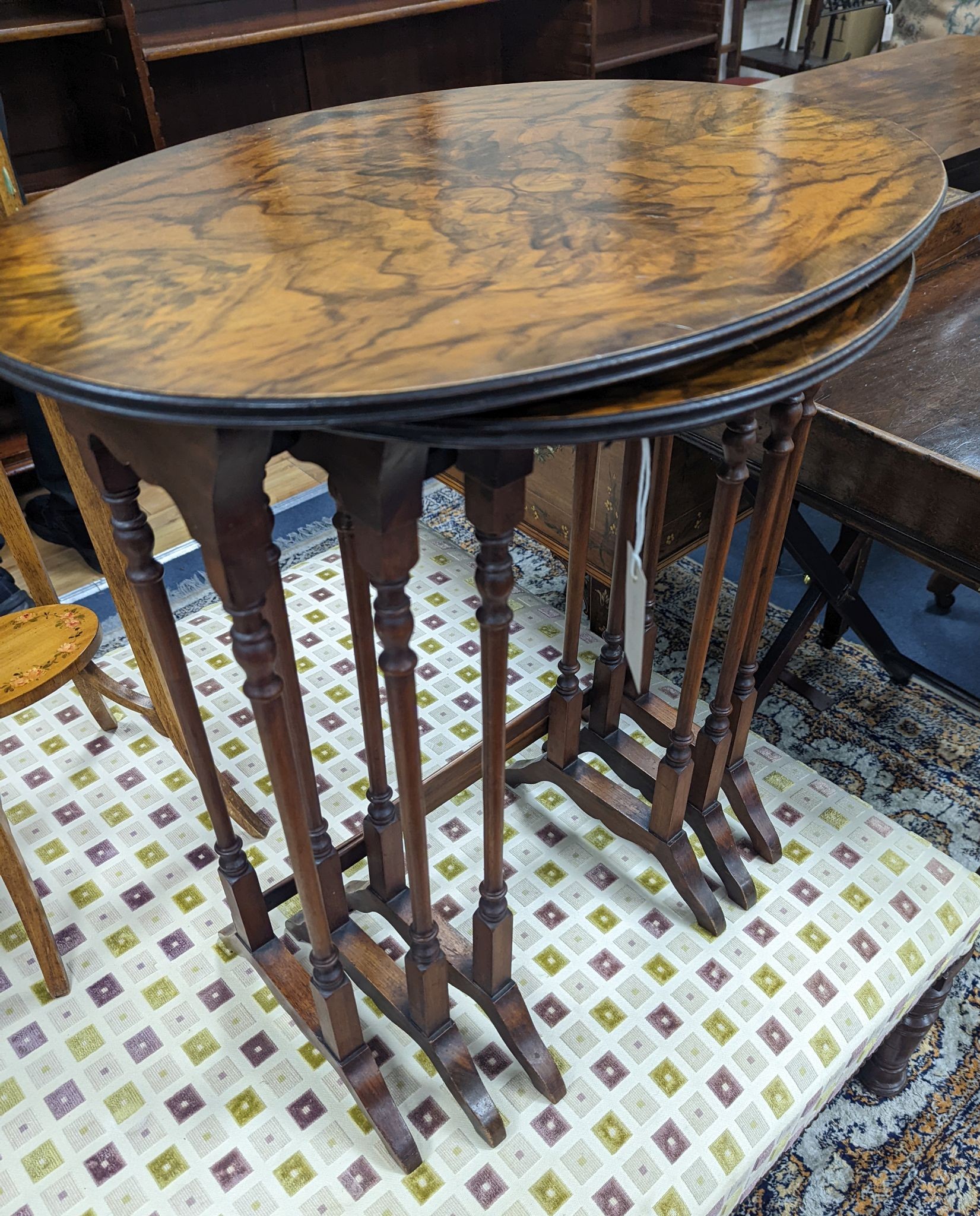 A nest of three oval and circular burr and simulated walnut tea tables, width 55cm, depth 37cm, height 60cm